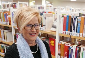Stefanie Oeding vor einem Bücherregal mit zwei Büchern in der Hand