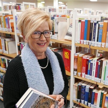 Stefanie Oeding vor einem Bücherregal mit zwei Büchern in der Hand