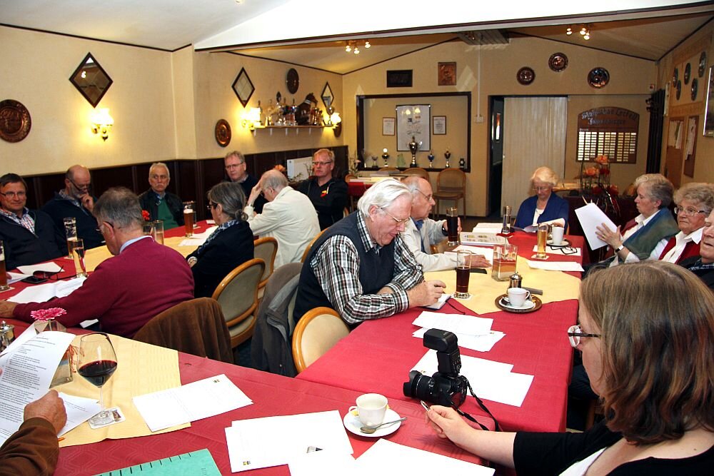 Menschen die an Tischen sitzen und auf Zetteln lesen