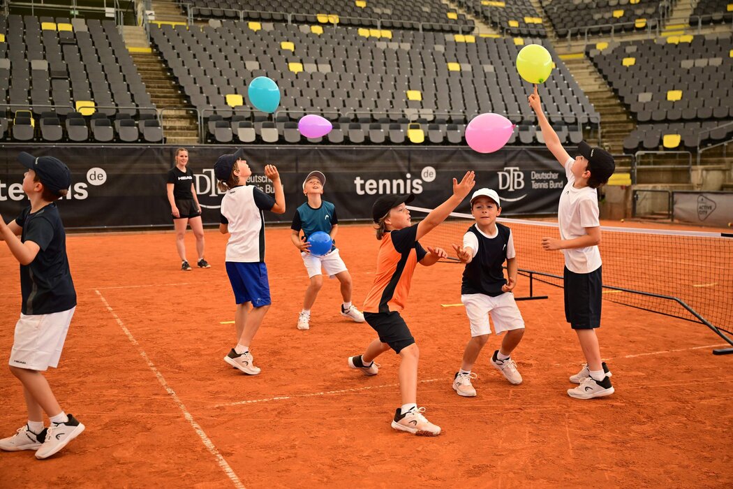 Kinder beim Tennistraining üben Koordination mit Luftballons